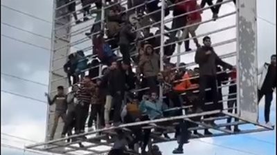 بروح وعزيمة.. فلسطينيون يتسلقون لوحة إعلانية لـ مشاهدة تسليم الأسرى الإسرائيليين