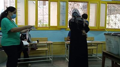 سيدة تحمل طفلها أثناء تصويتها بانتخابات النواب بالمنتزة في الإسكندرية