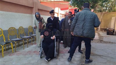 أمن الفيوم يساعد مسنة على كرسي متحرك للإدلاء بصوتها بلجنة كفور النيل