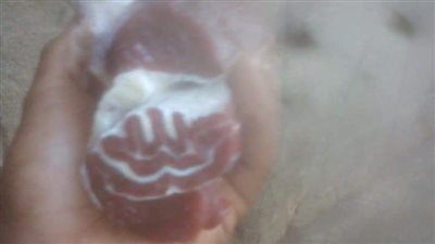 جزار بسوهاج يحمل قطعة لحم تظهر عليها لفظ الجلالة