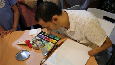 فنان تشكيلي من ذوى الهمم يرسم دون يديه في جناح الأزهر بمعرض الإسكندرية 