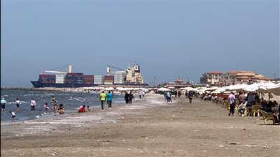 السفن تمر بجانب المصطافين.. شاطئ بورسعيد يشهد إقبالًا متوسطًا بالتزامن مع ارتفاع درجات الحرارة |صور وفيديو