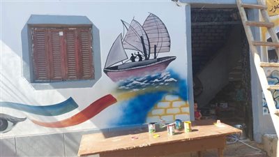 يحارب التطرف بالفن الشعبي.. فنان قبطي بالمنيا يرسم على منازل الحجاج لإسعادهم