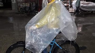 المطر أحلى من طابور العاطلين.. شاب يعمل دليفري وسط طقس سيئ بكفر الشيخ (صور)