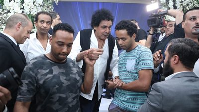 مستندًا على أحد الأشخاص.. أحدث ظهور لمحمد منير بحفل زفاف الإعلامية سالي عبد السلام 