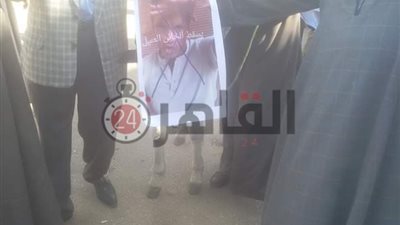 احتفالًا بعيد الشرطة.. العشرات يرفعون صور المقاول محمد علي على حمار ويدهسونها بالأقدام فى قنا (فيديو)