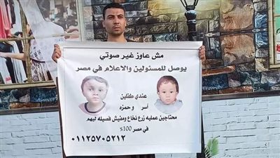 يحمل لافتة ويتجول في الشوارع.  شاب سوهاجي يستغيث لعلاج  طفليه من مرض خطير| صور